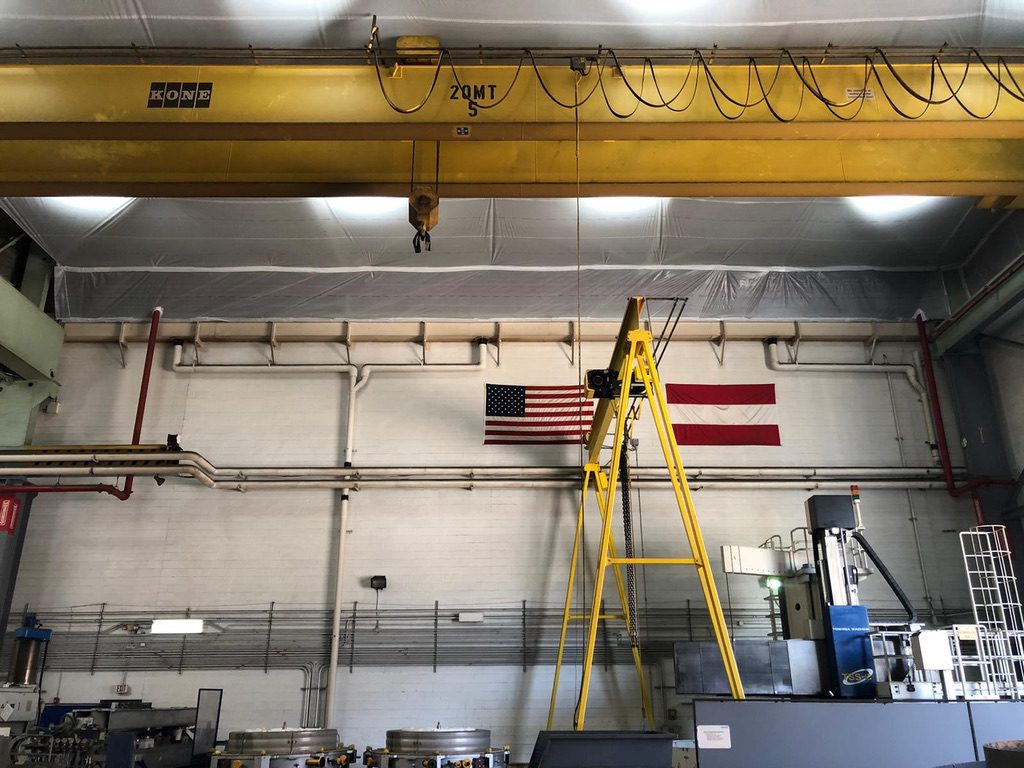 A yellow ladder in an industrial setting with a crane.