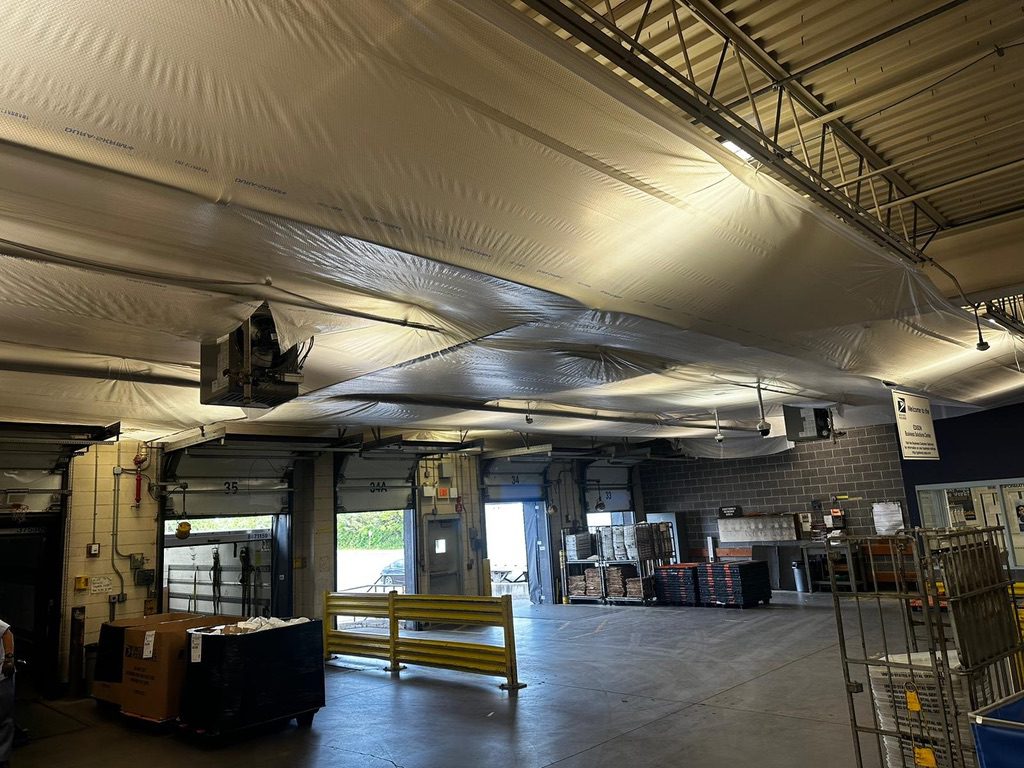 A warehouse with many boxes and lights on the ceiling.