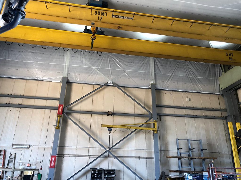 A crane is hanging in the middle of an industrial building.